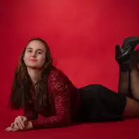 Eine junge Frau posiert liegend auf einer roten Fotostudiowand